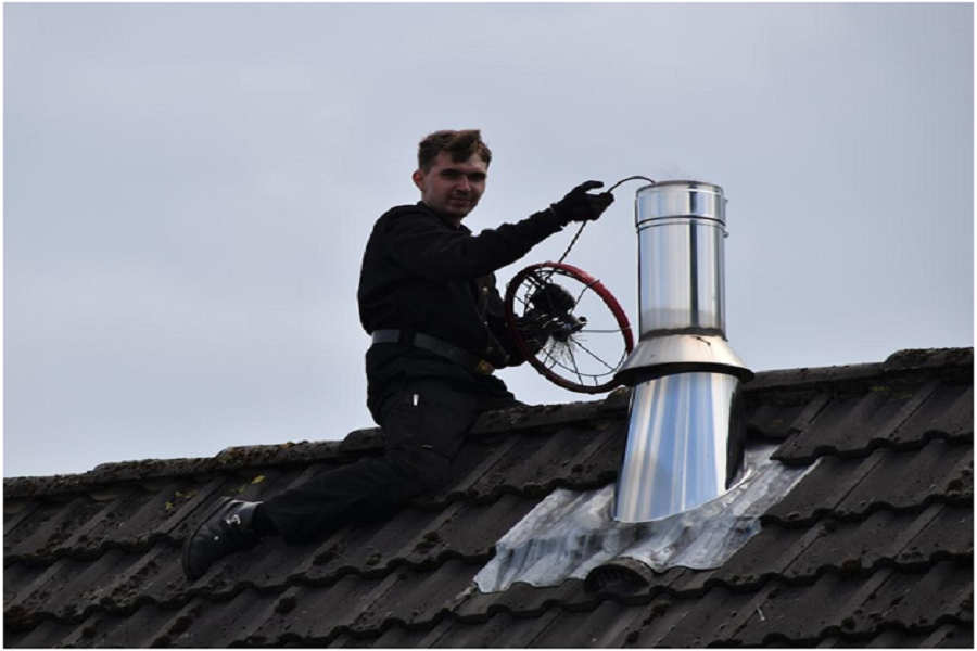 A man sweeping a chimney with his tools. 