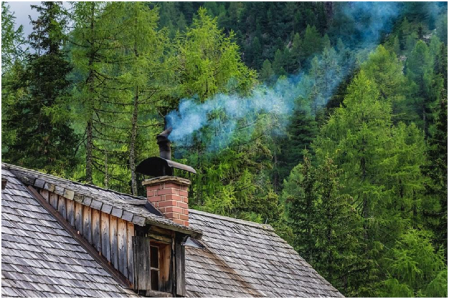 A house with a chimney with smoke coming out of it.