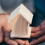 Real estate agent holding a mini wooden house